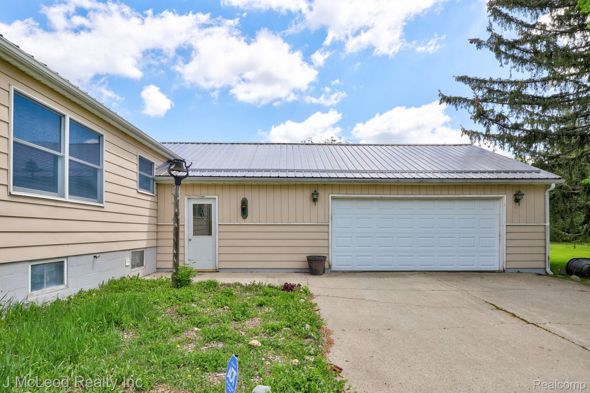 69 West Snover Road Mayville, MI 48744 - Photo 33 of 46 Metal roof, attached garage, concrete driveway, exterior lighting fixtures, and basement windows