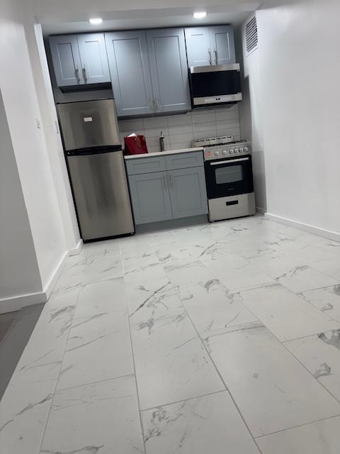 44-05 Macnish Street, Unit 1E Queens, NY 11373 - Photo 2 of 7 a kitchen with granite countertop a stove a microwave and a refrigerator