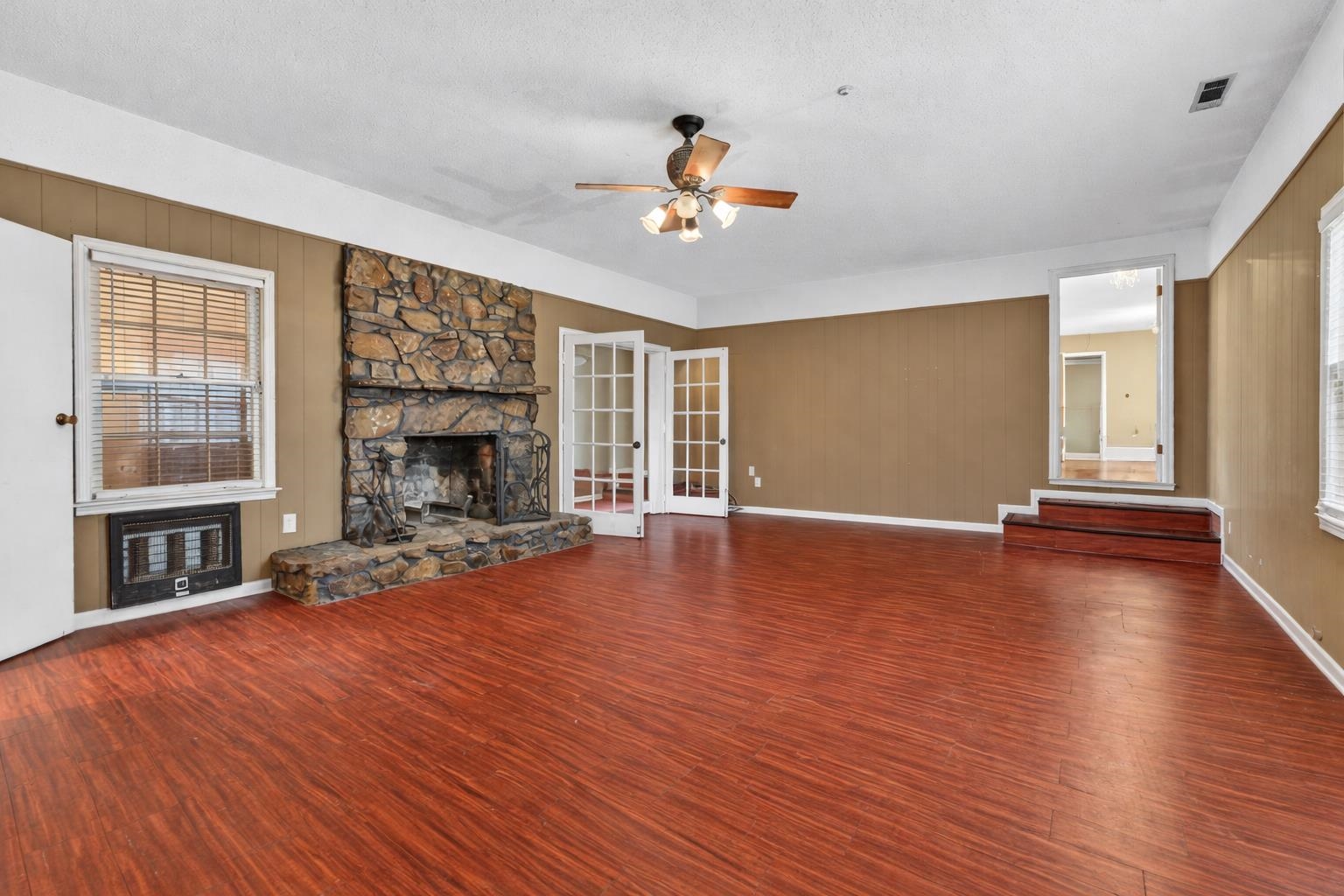 700 North Reid Hooker Road Eads, TN 38028 - Photo 13 of 20 Unfurnished living room featuring ceiling fan, a fireplace, dark wood-style floors, heating unit, and wood walls