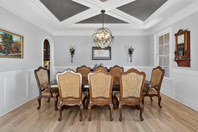 a kitchen with granite countertop a stove a sink dishwasher a dining table and chairs with wooden floor