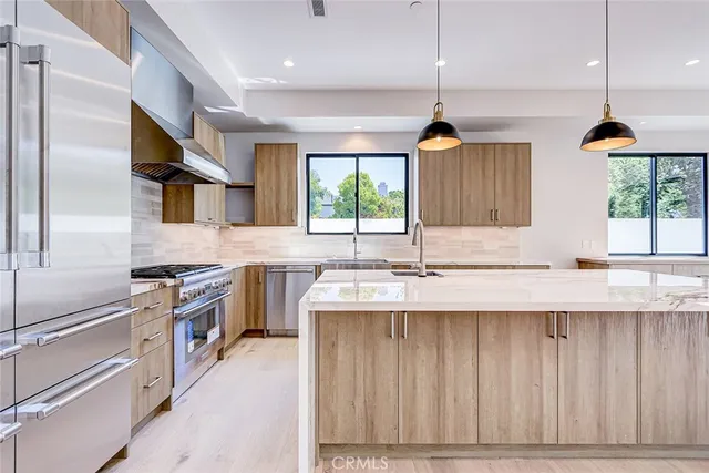 a kitchen with kitchen island granite countertop a stove a sink a refrigerator and a wooden floor