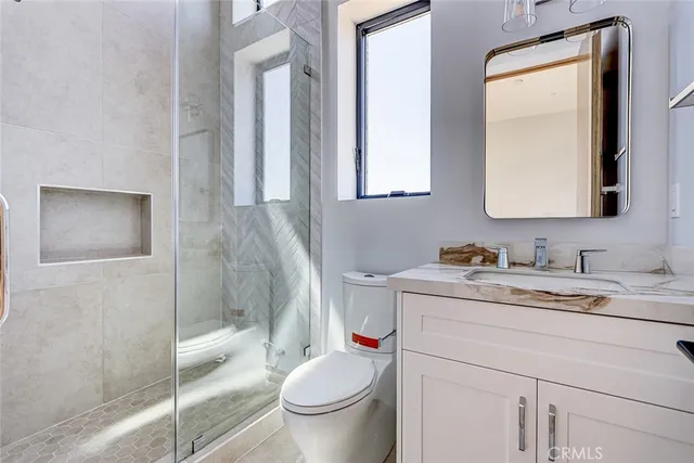 a bathroom with a granite countertop sink mirror vanity and toilet