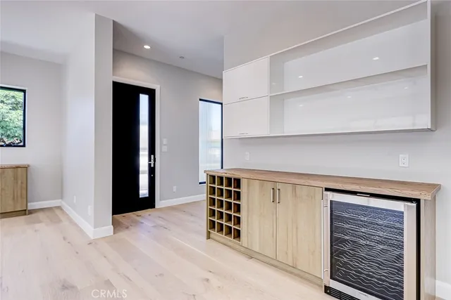an empty room with wooden floor cabinet and windows