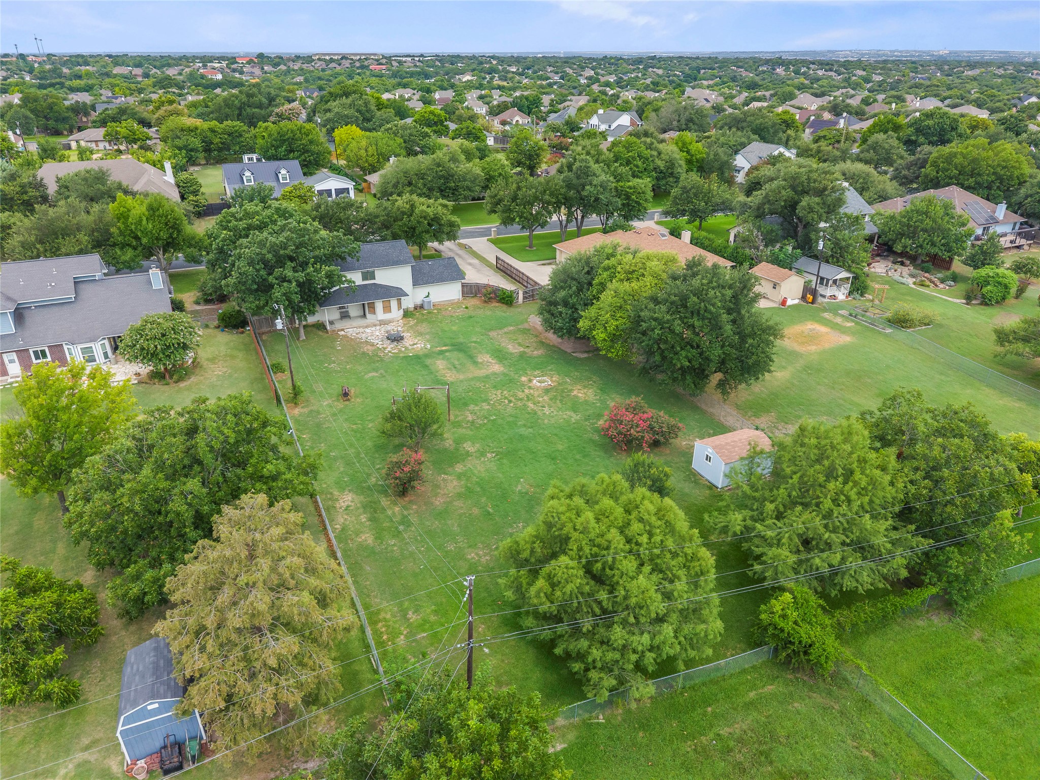 1329 Quail Ravine Round Rock, TX 78664 - Photo 19 of 39 A spacious backyard lawn surrounded by mature trees offers ample space for outdoor activities.