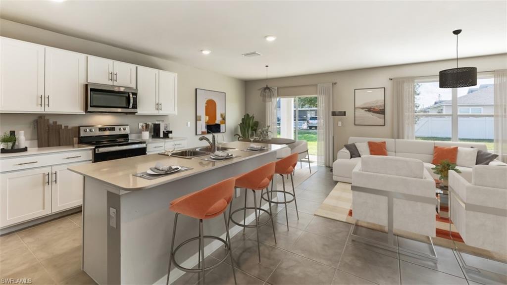 17782 Shade Tree Loop Punta Gorda, FL 33982 - Photo 25 of 26 Kitchen featuring stainless steel appliances, an island with sink, open floor plan, white cabinets, and pendant lighting