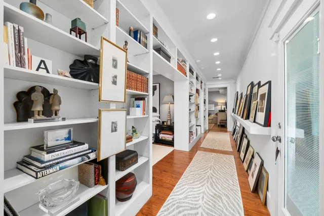 a hallway with lots of white cabinets and wooden floor