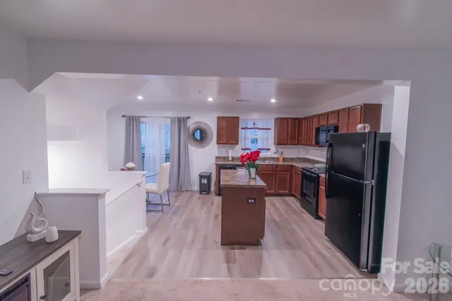 a kitchen with stainless steel appliances kitchen island granite countertop a refrigerator stove top oven and sink