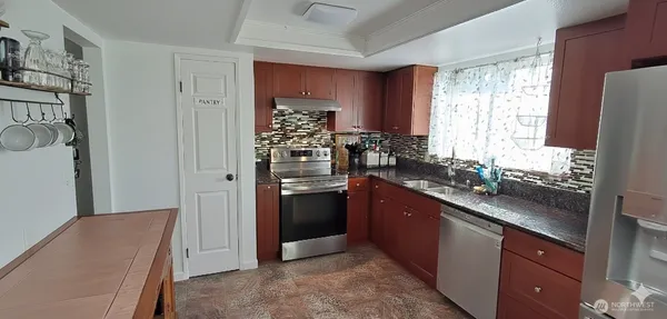 a kitchen with stainless steel appliances kitchen island granite countertop a refrigerator and a sink