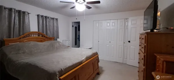 a bedroom with a bed and a flat tv screen on dresser