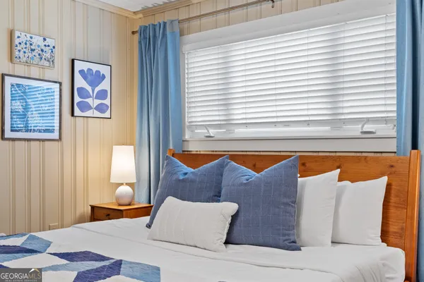 a bedroom with a bed a dresser and wooden floor