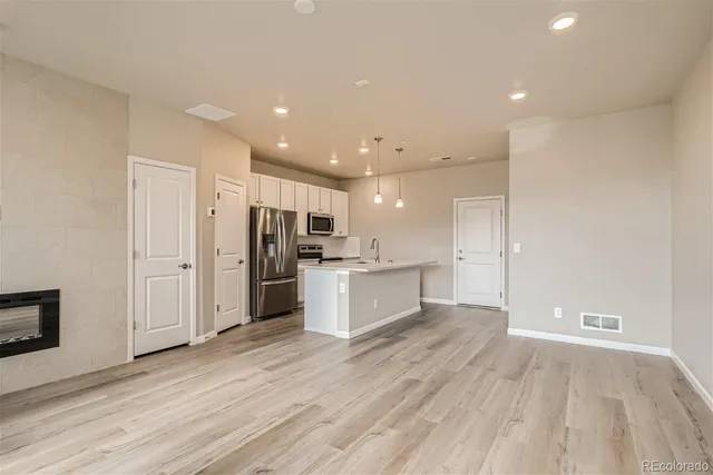 a large kitchen with a lot of counter top space stainless steel appliances and a ceiling fan