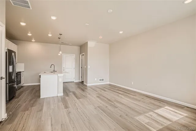 a view of a kitchen with a sink and dishwasher a refrigerator with wooden floor