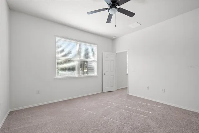 an empty room with a window and a fan