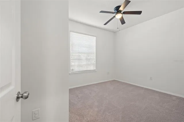 an empty room with a window and a ceiling fan