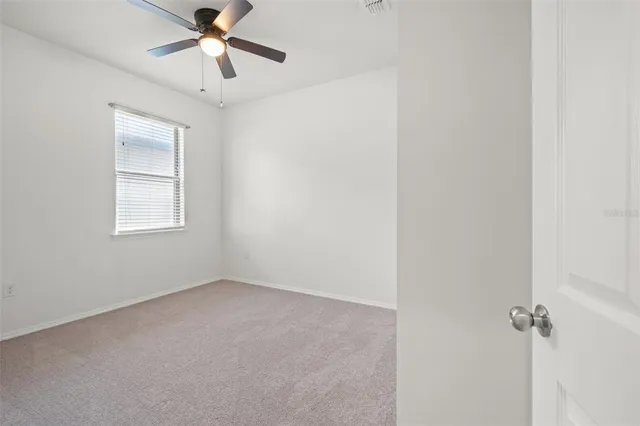 an empty room with a window and a fan