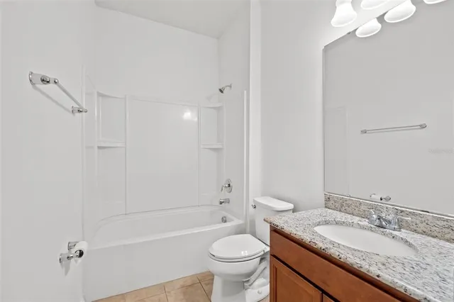 a bathroom with a granite countertop sink a toilet a mirror and shower