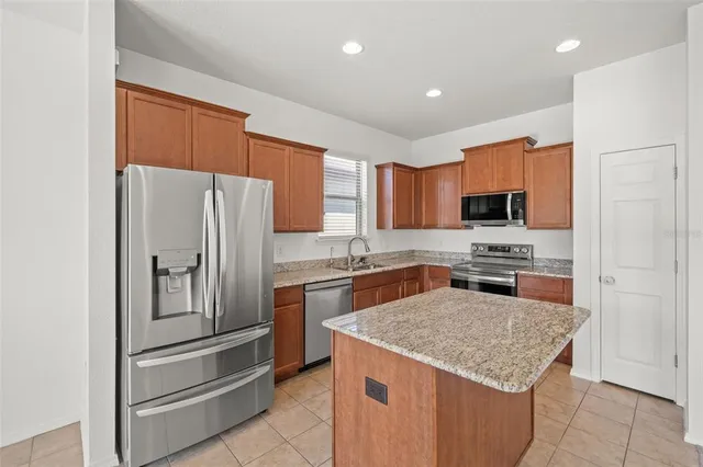 a kitchen with stainless steel appliances granite countertop a refrigerator a stove and a sink