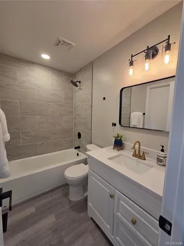 a bathroom with a toilet a sink a tub and mirror
