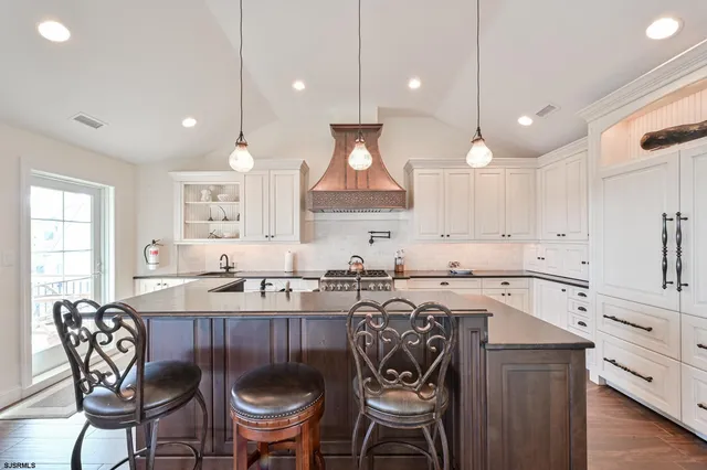 a kitchen with stainless steel appliances granite countertop a stove a sink a oven a dining table and chairs