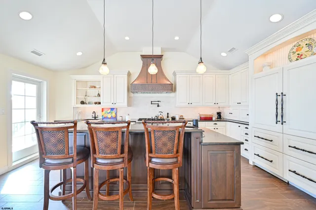 a kitchen with stainless steel appliances kitchen island granite countertop a wooden floor and white cabinets