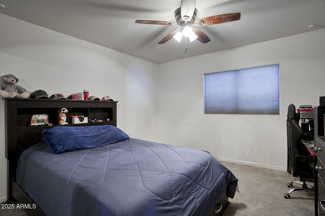 12677 North 77th Drive Peoria, AZ 85381 - Photo 10 of 25 a bedroom with a bed and a chandelier