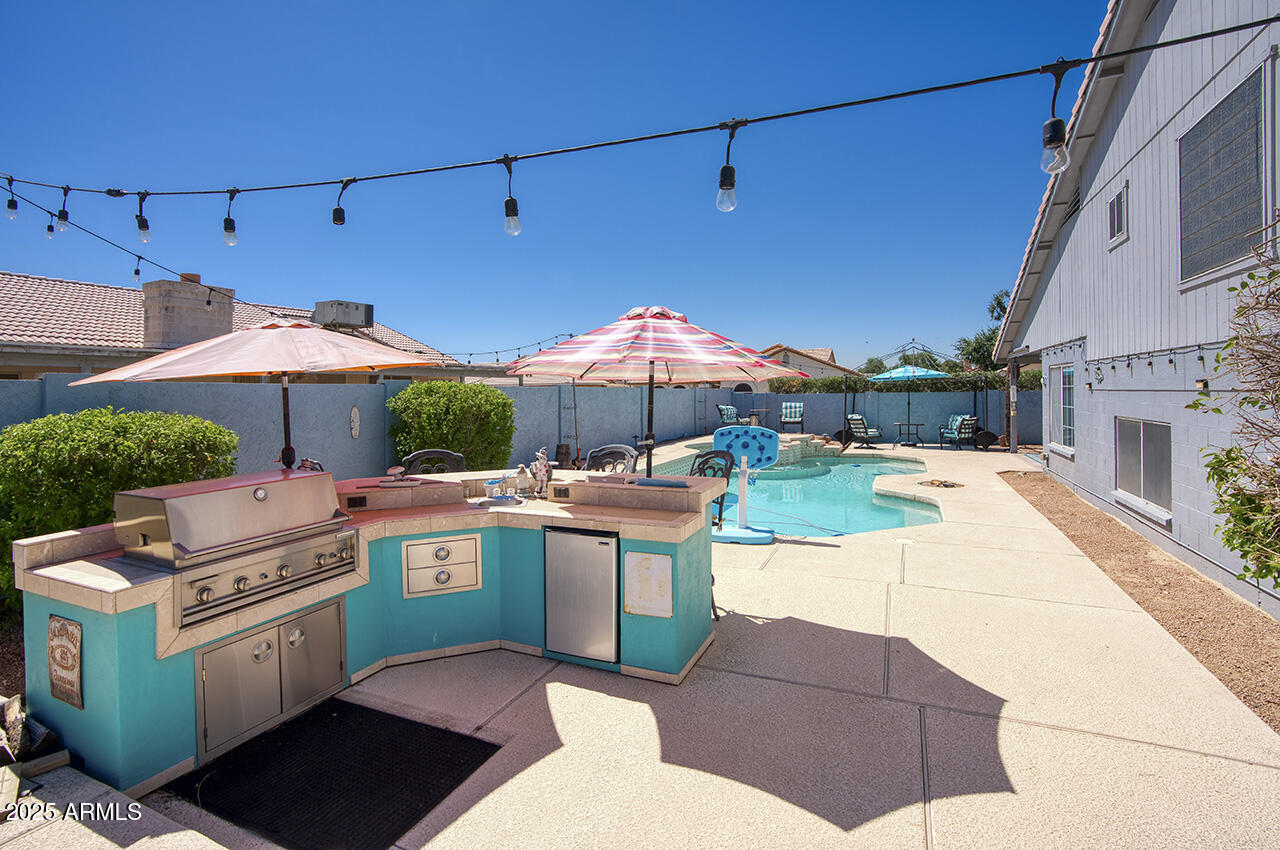 12677 North 77th Drive Peoria, AZ 85381 - Photo 22 of 25 a patio with a table and chairs under an umbrella