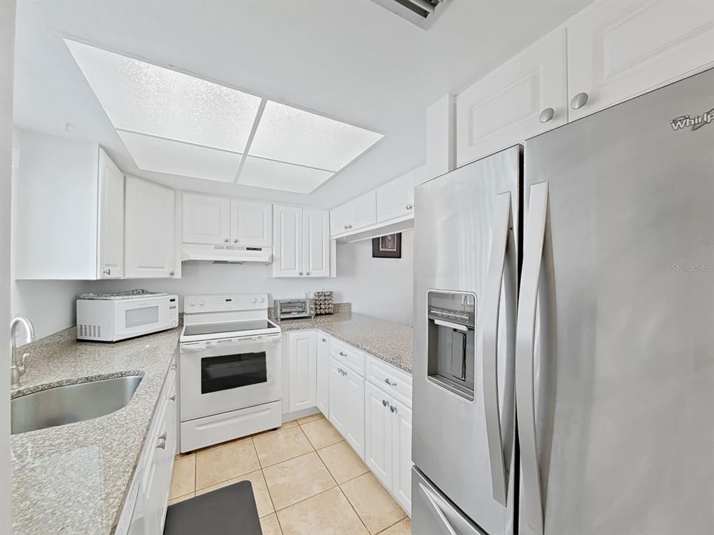 215 Valencia Boulevard, Unit 213 Largo, FL 33770 - Photo 7 of 21 a kitchen with stainless steel appliances granite countertop a refrigerator sink and stove
