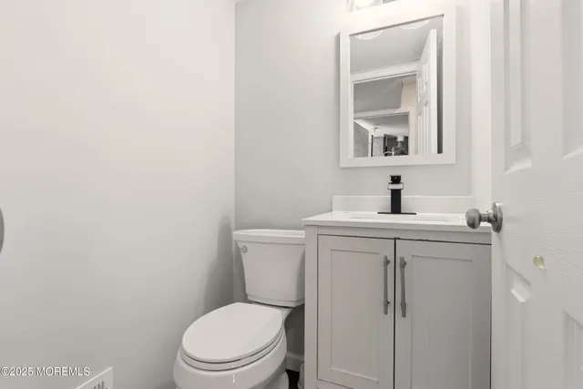 a bathroom with a toilet sink vanity and mirror