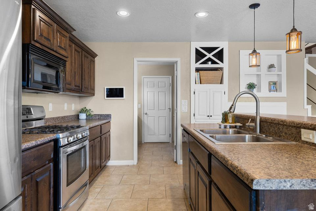 225 Falcon Court Ivins, UT 84738 - Photo 8 of 47 Kitchen with stainless steel appliances, dark wood finish cabinetry, a center island with sink, hanging light fixtures, and a textured ceiling