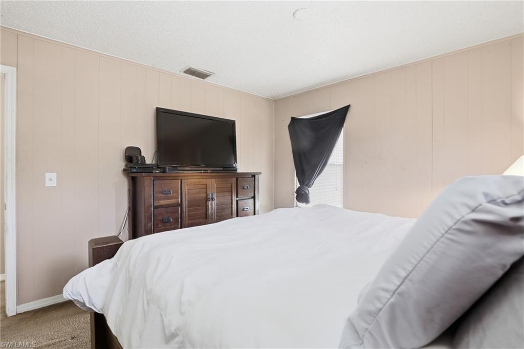 318 Bellair Road Fort Myers, FL 33905 - Photo 15 of 29 a bedroom with a bed and a flat screen tv