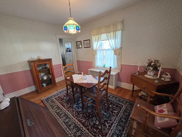 a dining room with wooden floor a chandelier a wooden table and chairs
