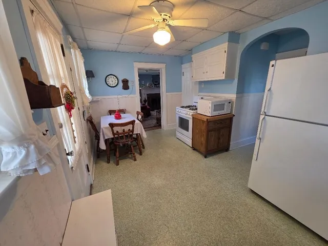 a living room with furniture and a refrigerator