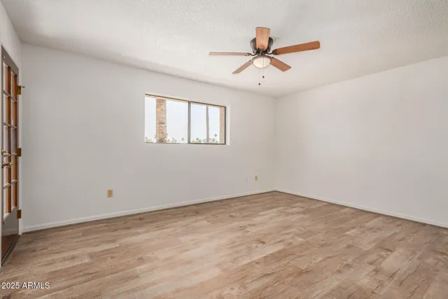 a view of empty room with wooden floor and window