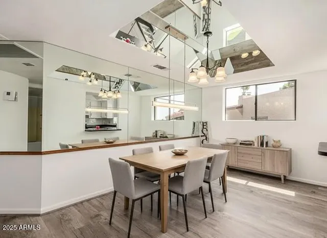 a dining room with wooden floor a chandelier a wooden table and chairs