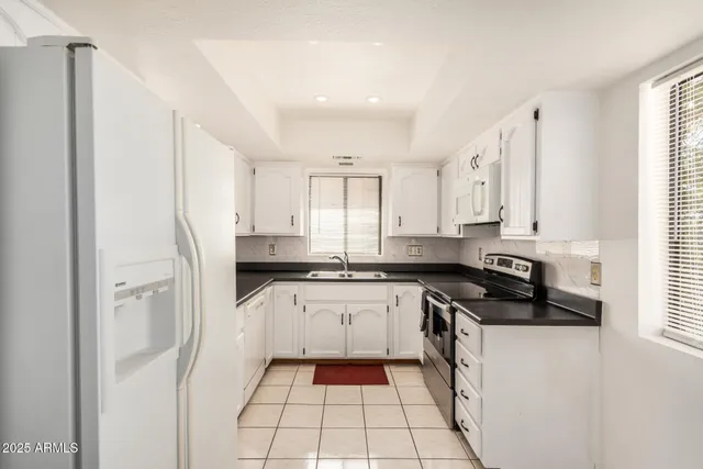 a white kitchen with granite countertop a sink a stove and cabinets