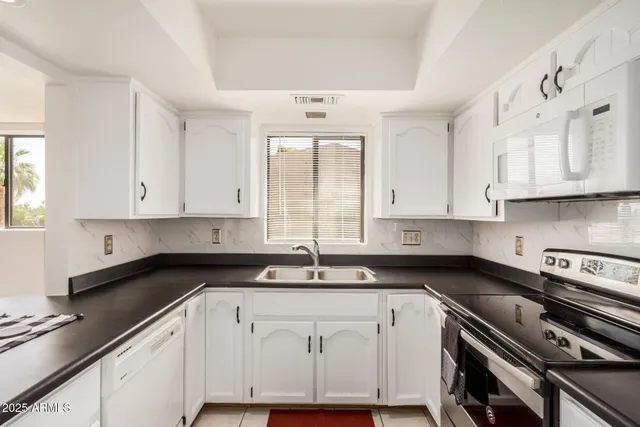 a kitchen with granite countertop white cabinets and white appliances