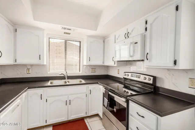 a kitchen with stainless steel appliances granite countertop a stove a sink and a microwave