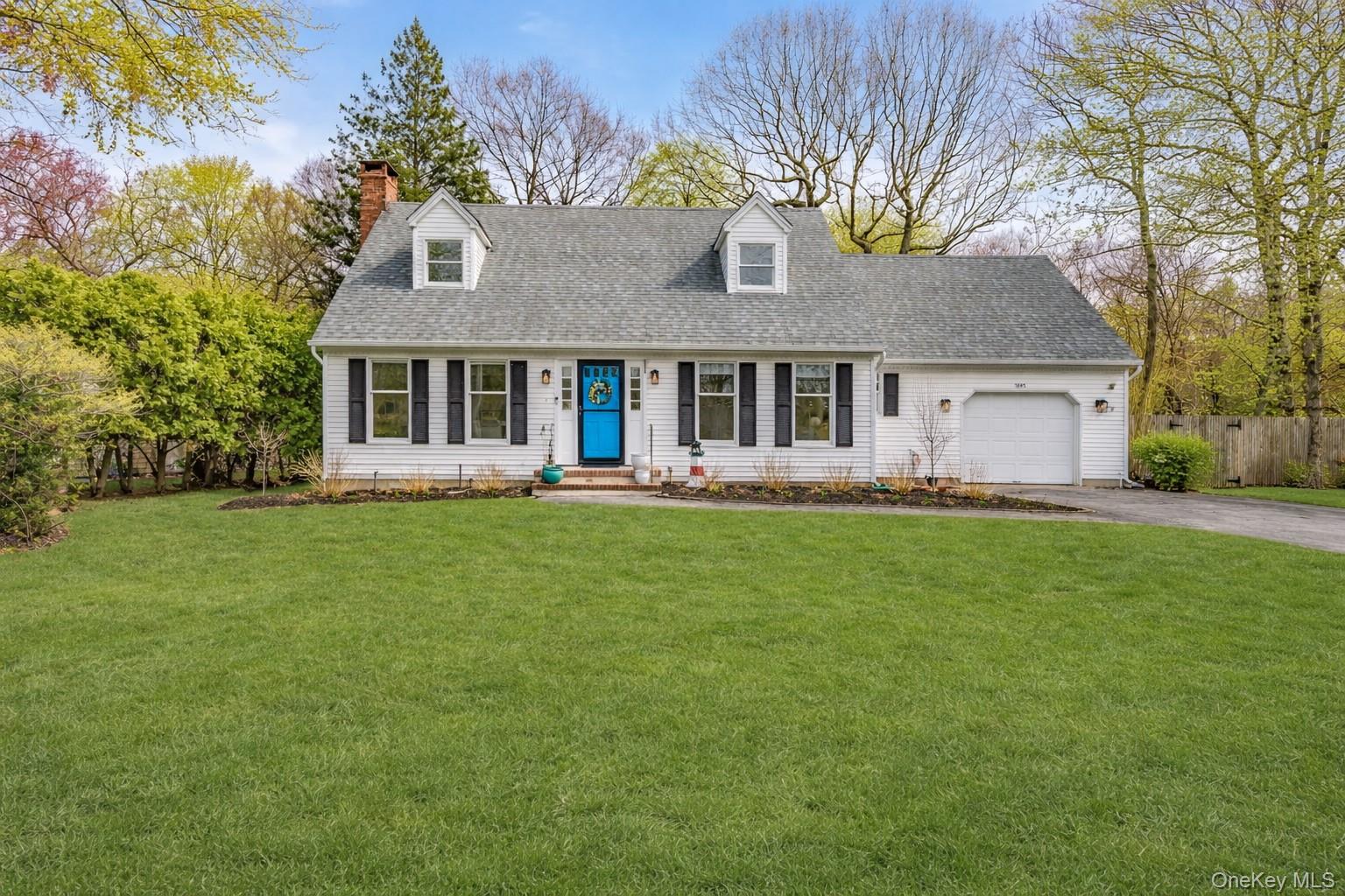 Classic cape cod with yard, driveway, garage and landscaping