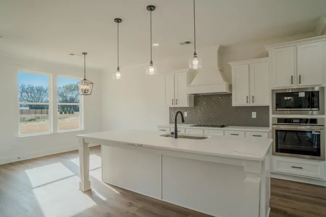 a kitchen with stainless steel appliances granite countertop a sink a stove and a refrigerator