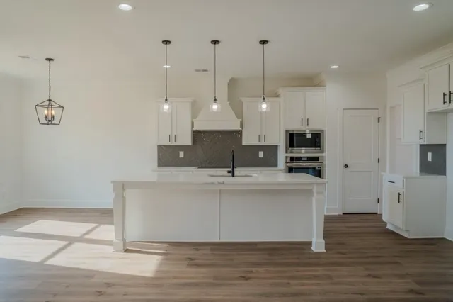 a view of kitchen with stainless steel appliances granite countertop a sink a refrigerator a center island a stove and a window