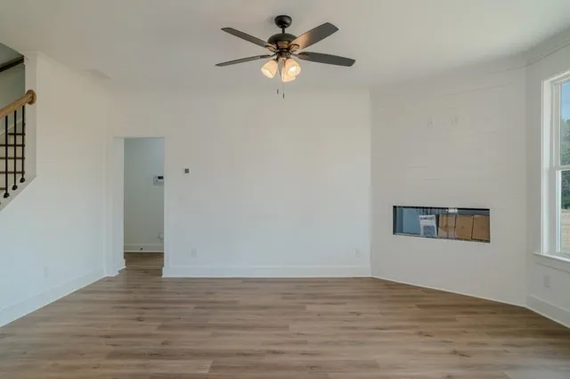 a view of an empty room with window and a ceiling fan