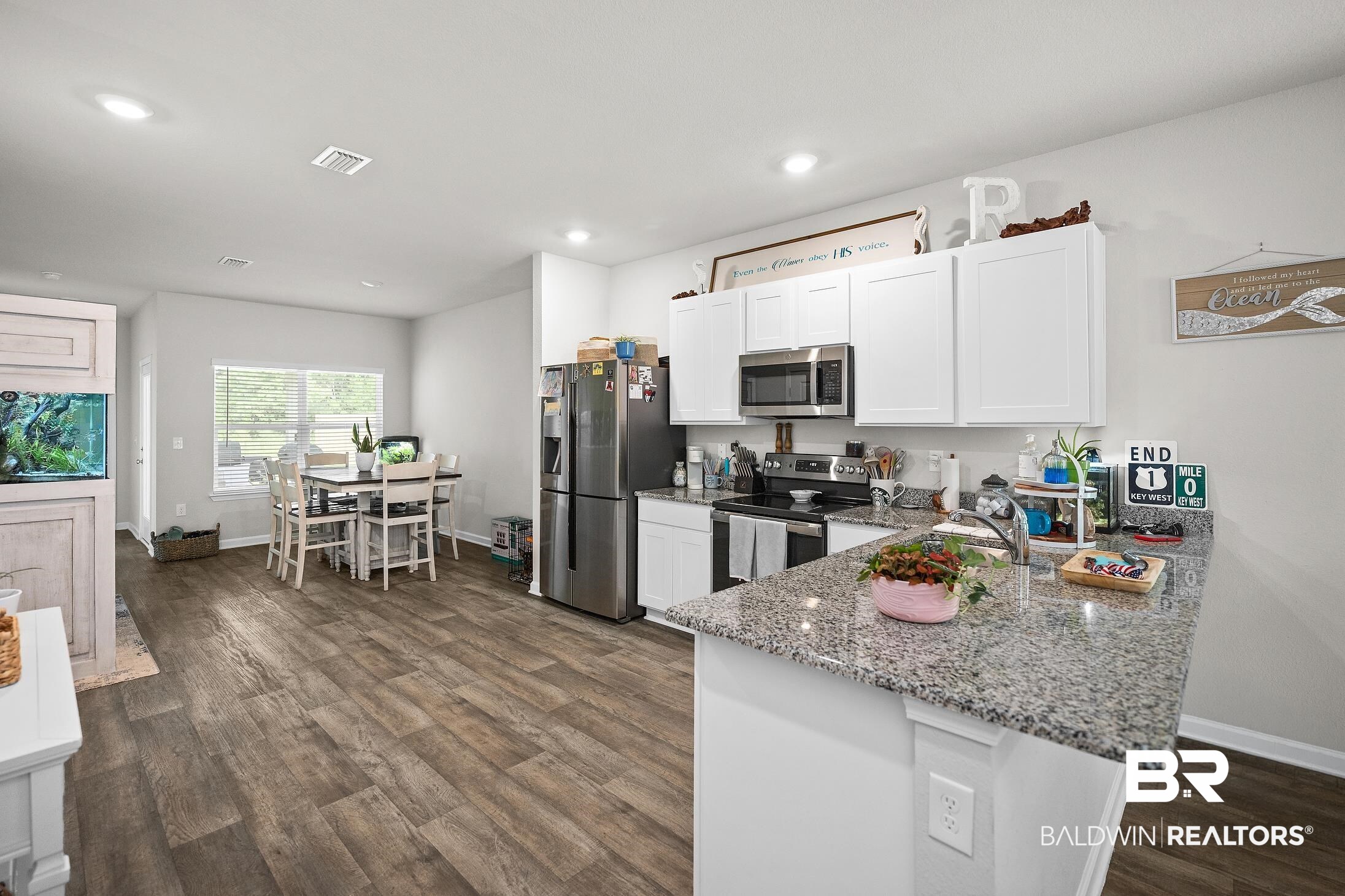 23997 Veranda Circle Elberta, AL 36530 - Photo 6 of 28 Open-concept kitchen and dining area featuring wood-finish flooring, white cabinetry, stainless steel appliances, and a granite-style countertop on the kitchen island