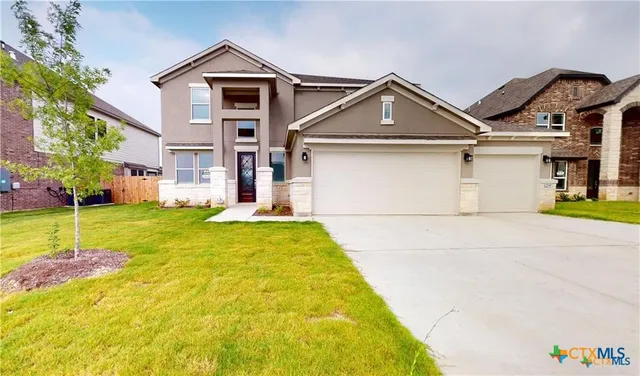 a view of a white house with a small yard and large tree