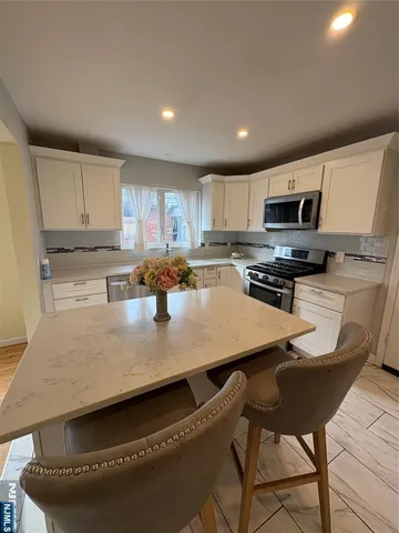 a kitchen with kitchen island granite countertop a stove a sink a microwave a refrigerator and cabinets