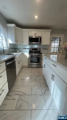 a large kitchen with stainless steel appliances granite countertop a stove a sink and a microwave