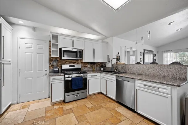 a kitchen with stainless steel appliances granite countertop a stove top oven a sink and dishwasher