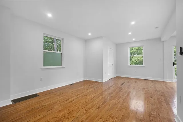 an empty room with wooden floor and windows
