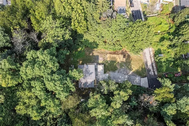 an aerial view of residential house with outdoor space and trees all around