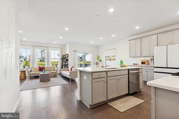 a kitchen with a sink dishwasher stove and white cabinets with wooden floor