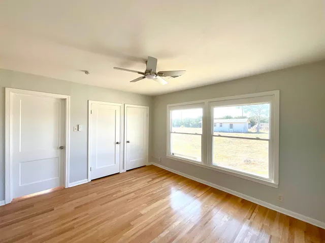 a view of empty room with wooden floor and fan